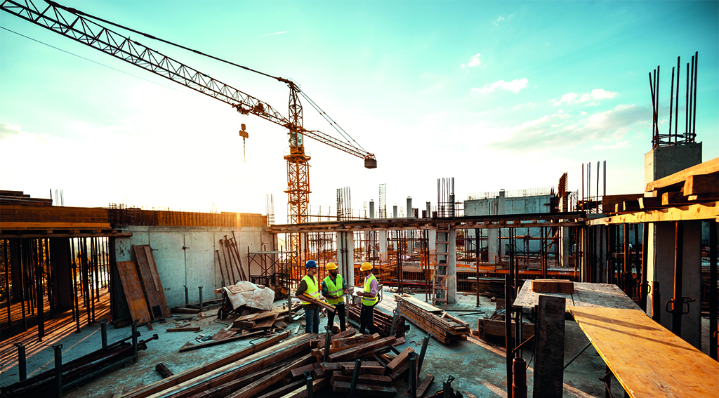 Construction industry concept - architects and engineers discussing work progress between concrete walls, scaffolds and cranes.