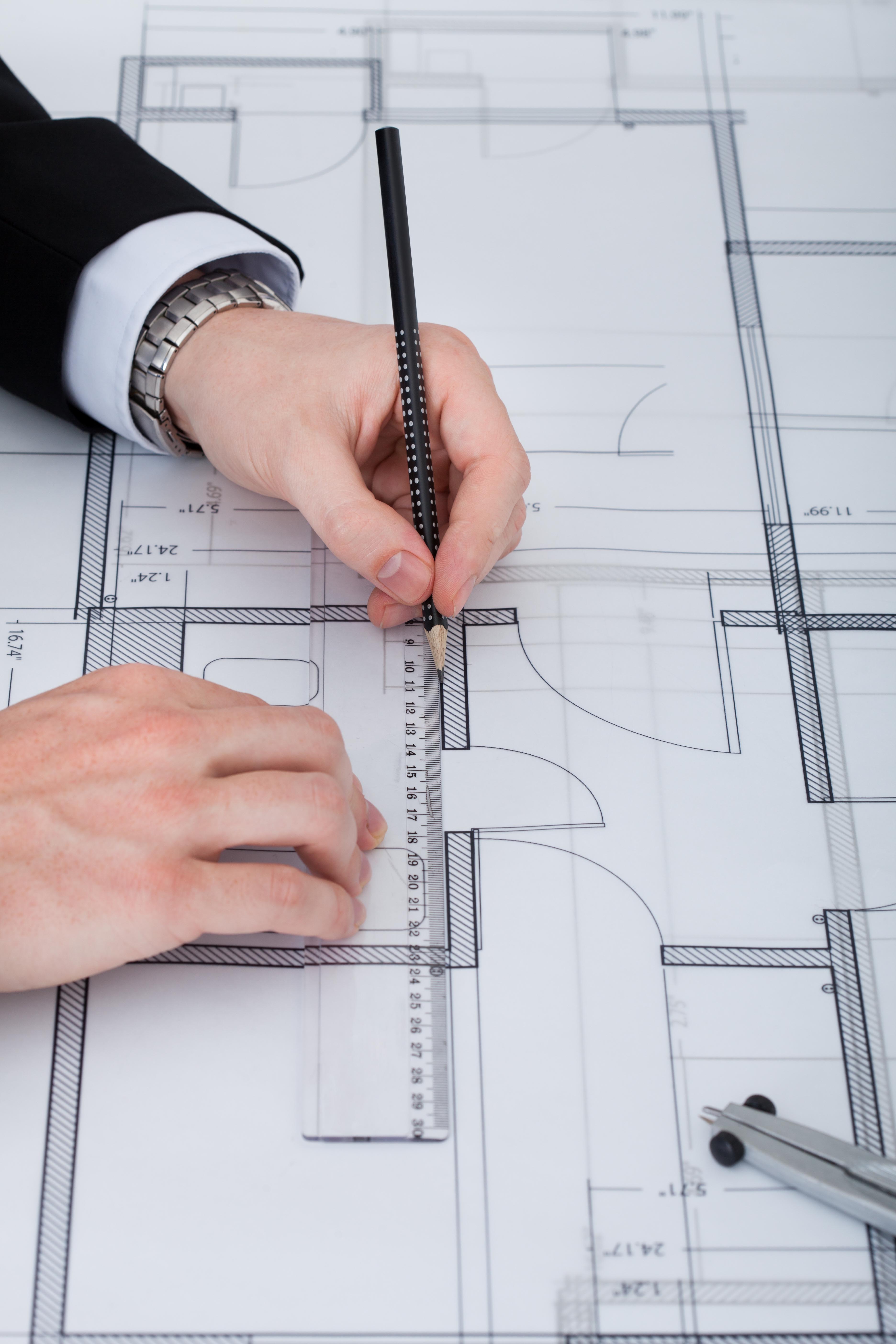 Cropped image of businessman working on blueprint at desk in office