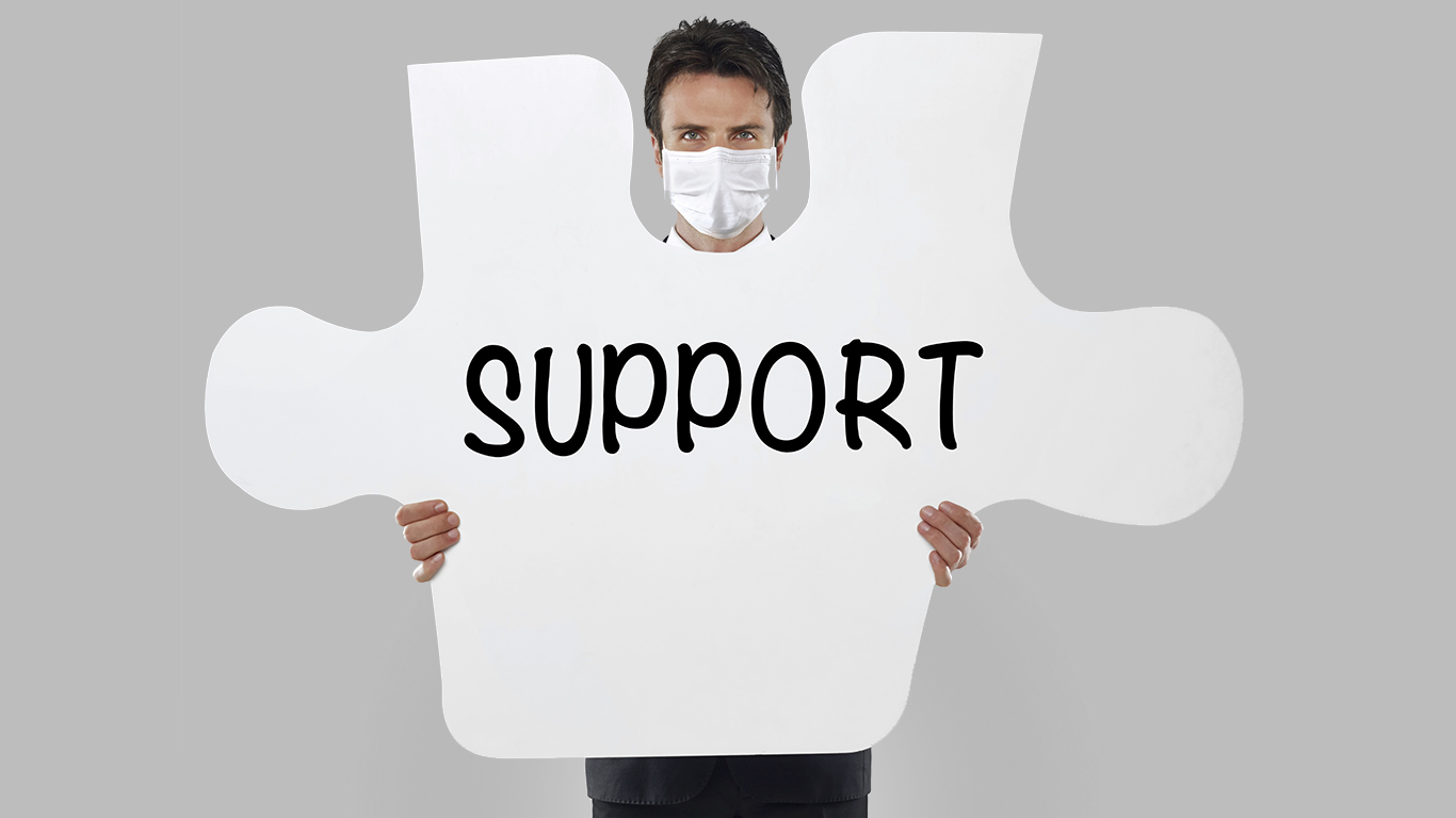 Businessman wearing a mask holding a missing piece of a puzzle with “Support” text